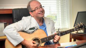 Dr. Scott Miller holding a guitar